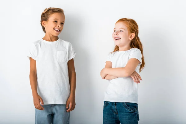 Niños alegres de pie y sonriendo en blanco - foto de stock