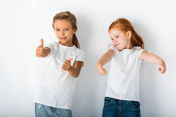 Adorable kids smiling and showing thumbs up on white — Stock Photo