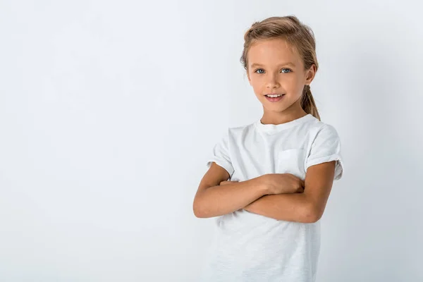Щаслива дитина, що стоїть з схрещеними руками на білому — стокове фото