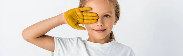 Panoramic shot of kid with paint on hand covering face isolated on white — Stock Photo