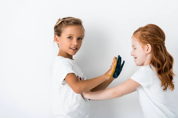 Niños felices con pintura en las manos jugando en blanco - foto de stock