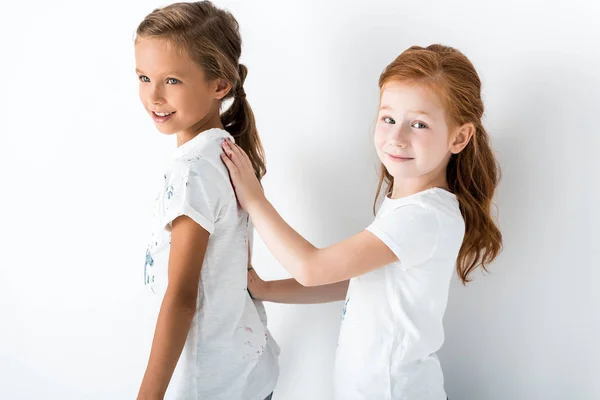 Mignon rousse enfant toucher enfant tandis que debout sur blanc — Photo de stock