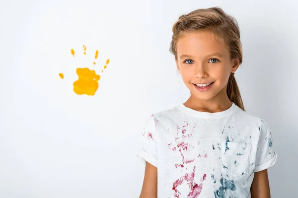 Happy kid smiling near yellow hand print on white — Stock Photo