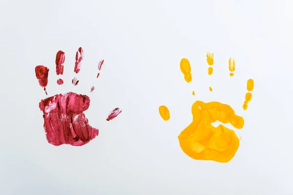 Empreintes de main rouges et jaunes sur blanc — Photo de stock