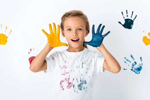 Garoto animado com tinta nas mãos perto impressões da mão no branco — Fotografia de Stock