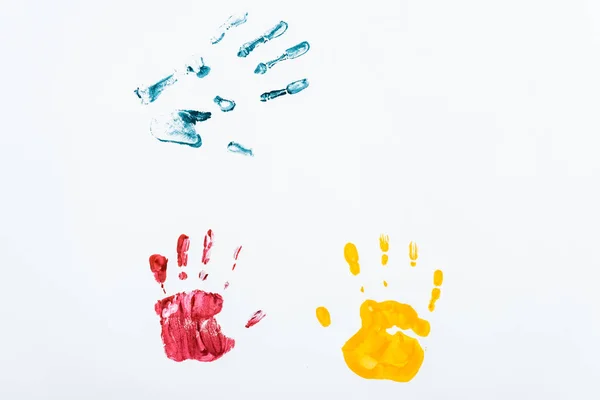 Impresiones de mano rojas, azules y amarillas sobre blanco - foto de stock