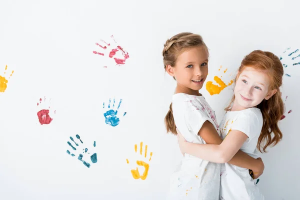 Joyeux enfants étreignant près des empreintes de main sur blanc — Photo de stock