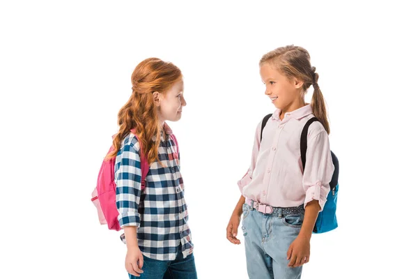 Щасливі школярки з рюкзаками, які дивляться один на одного ізольовані на білому — стокове фото