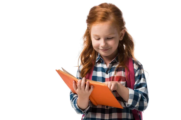 Fröhliche rothaarige Schülerin liest Buch isoliert auf weiß — Stockfoto