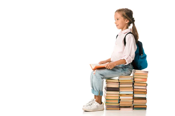 Весела дитина сидить на книгах і посміхається на білому — стокове фото