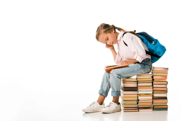 Милий школяр сидить на книгах і читає на білому — стокове фото