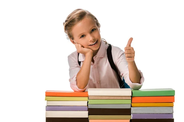 Allegro scolaro mostrando pollice verso l'alto vicino a libri colorati isolati su bianco — Foto stock