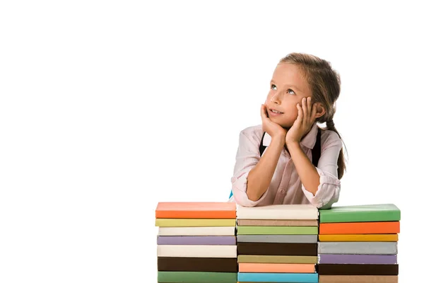 Dreamy schoolkid near colorful books isolated on white — Stock Photo
