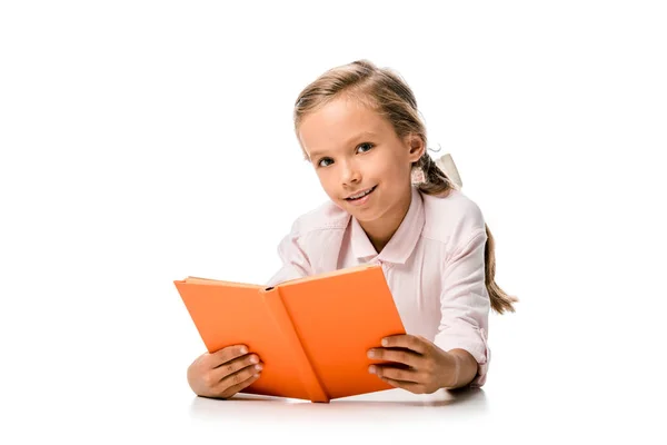 Glückliches Schulkind hält orangefarbenes Buch in der Hand und lächelt auf weiß — Stockfoto