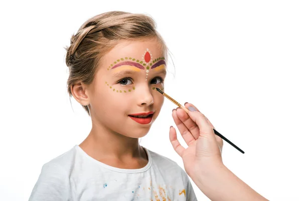 Cropped view of woman holding paintbrush near happy kid with face painting isolated on white — Stock Photo