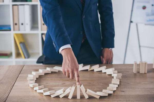 Partial view of risk manager stopping domino effect of falling wooden blocks — Stock Photo