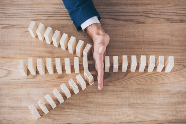 Cropped view of risk manager protecting wooden blocks from domino effect — Stock Photo