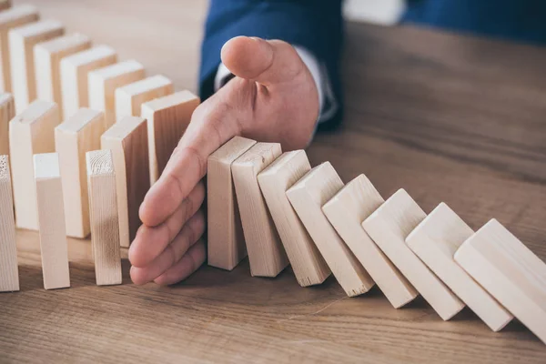 Partial view of risk manager blocking domino effect of falling wooden blocks — Stock Photo