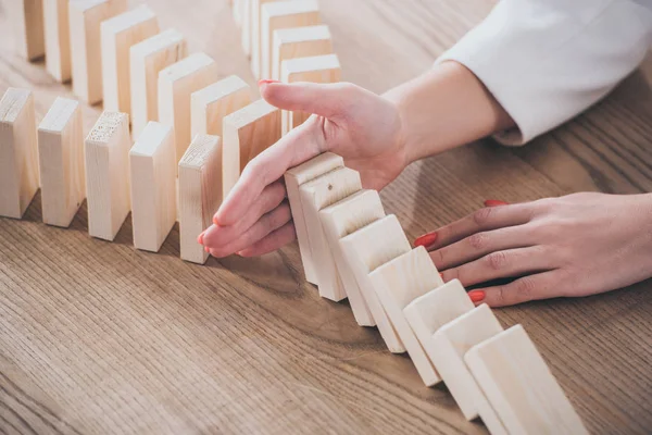 Partial view of risk manager blocking domino effect of falling wooden blocks — Stock Photo