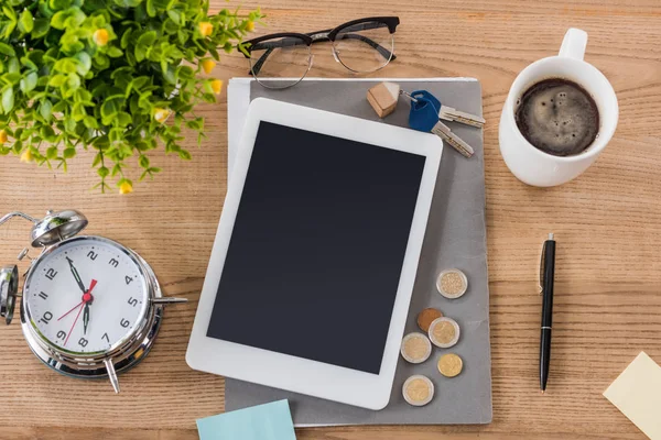 Ansicht des digitalen Tablets in der Nähe von Münzen, Schlüsseln, Kaffeebecher, Wecker, Stift, Gläsern und grünen Pflanzen — Stockfoto