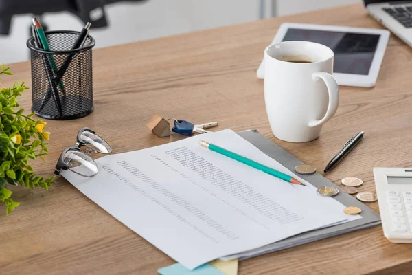 Document près de pièces de monnaie, clés, tasse de café, verres, tablette numérique et porte-stylo sur table en bois — Photo de stock