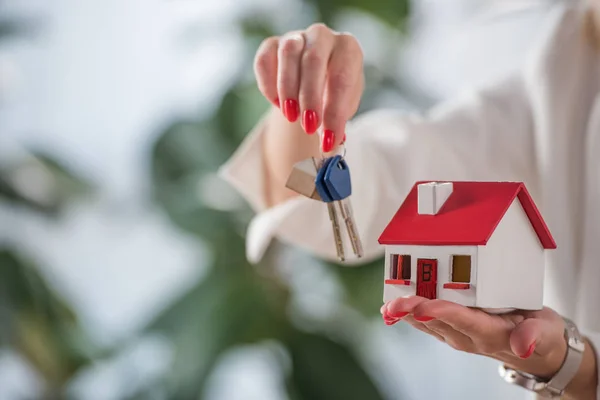 Partial view of businesswoman showing house model and keys — Stock Photo