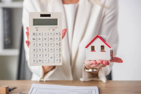 Vue partielle de la femme d'affaires montrant le modèle de maison et la calculatrice — Photo de stock