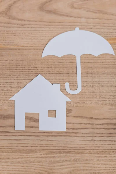 Верхний вид на дом из белой бумаги и зонтик на деревянном столе — стоковое фото