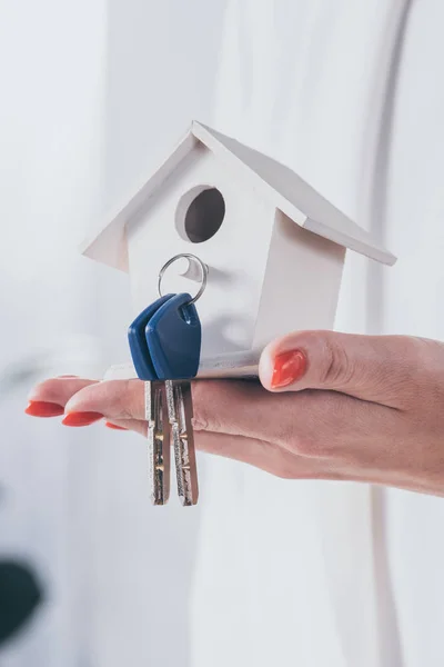 Частичный взгляд предпринимательницы, держащей модель дома с ключами — стоковое фото