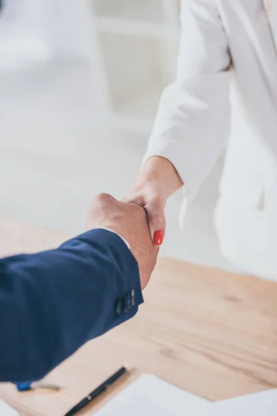 Visão parcial do empresário apertando as mãos com o cliente no escritório — Stock Photo