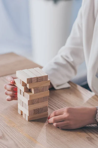 Cropped view of risk manager taking wooden block out of stack — Stock Photo