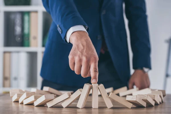 Cropped view of risk manager stopping domino effect of falling wooden blocks — Stock Photo