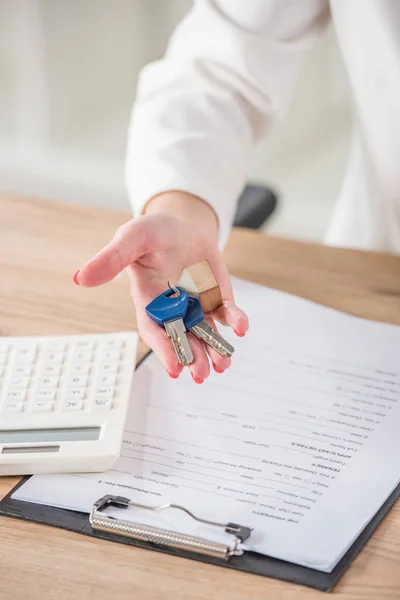 Abgeschnittene Ansicht einer Geschäftsfrau, die Hausschlüssel in der Nähe von Klemmbrett und Taschenrechner hält — Stockfoto