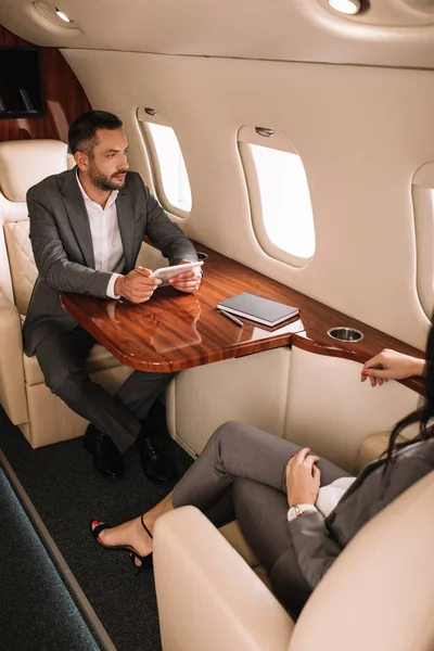 Cropped view of businesswoman near handsome businessman in plane — Stock Photo