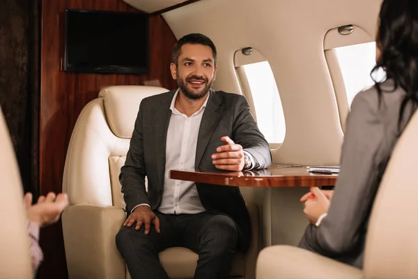 Cropped view of women sitting near happy businessman in first class — Stock Photo