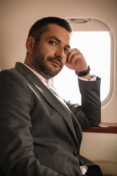 Handsome businessman sitting near airplane window in private jet — Stock Photo