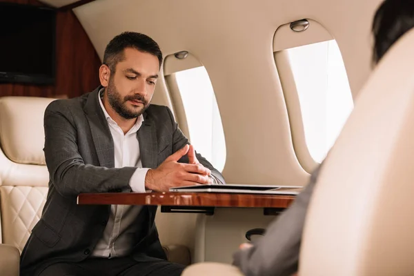 Selective focus of handsome businessman sitting near businesswoman in plane — Stock Photo