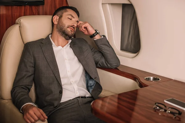 Enfoque selectivo de hombre de negocios con los ojos cerrados sentado en jet privado - foto de stock