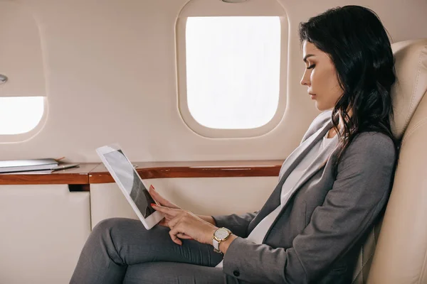 Side view of attractive businesswoman using digital tablet in private jet — Stock Photo