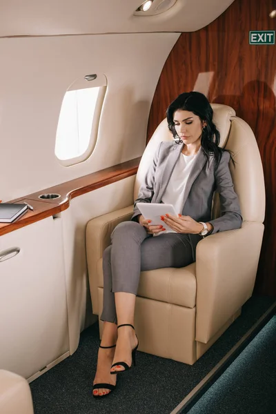 Приваблива бізнес-леді, дивлячись на цифровий планшет в приватному літаку — стокове фото