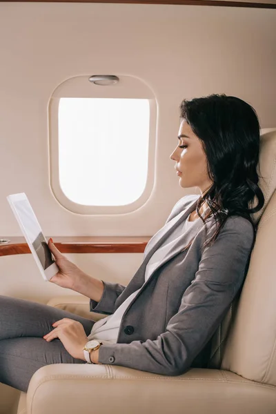 Вид збоку привабливої бізнес-леді з використанням цифрового планшета в приватному літаку — стокове фото