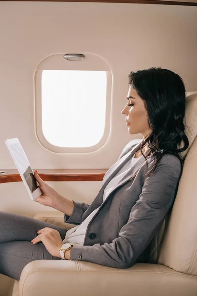 Seitenansicht attraktiver Geschäftsfrau mit digitalem Tablet im Privatjet — Stockfoto