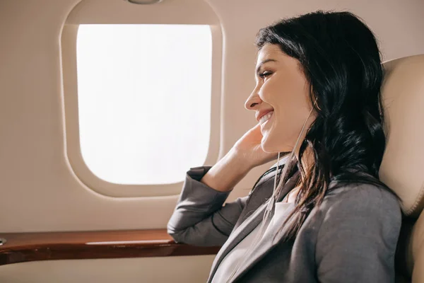 Femme d'affaires heureuse écoutant de la musique en jet privé — Photo de stock
