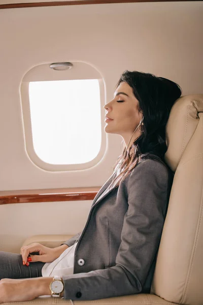 Vue latérale d'une femme d'affaires attrayante écoutant de la musique en jet privé — Photo de stock