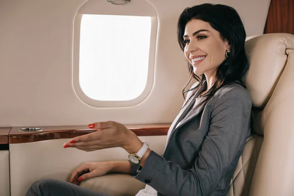 Selective focus of cheerful businesswoman gesturing in private jet — Stock Photo