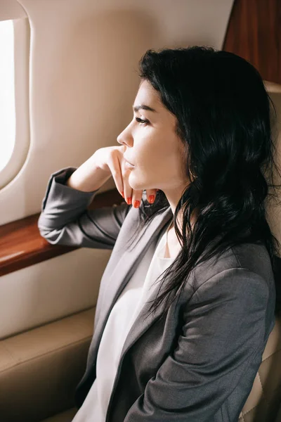 Attractive businesswoman looking at airplane window — Stock Photo