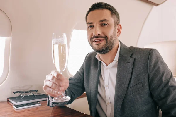 Bonito empresário segurando taça de champanhe em jato privado — Fotografia de Stock