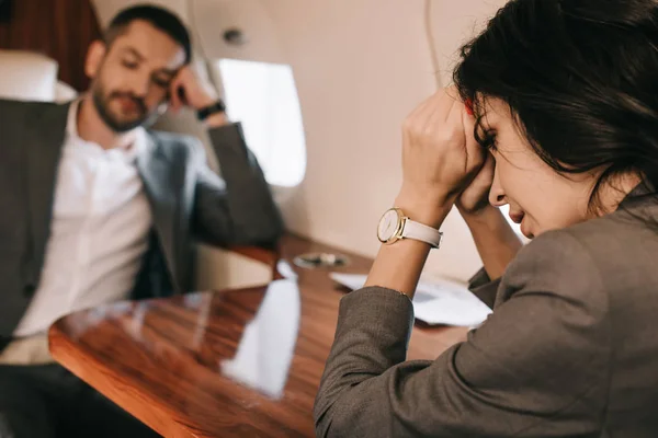 Selective focus of stressed woman with fear of fright sitting with businessman in private jet — Stock Photo