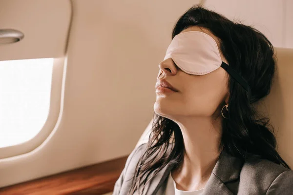 Mujer de negocios en la máscara de dormir sentado en jet privado - foto de stock