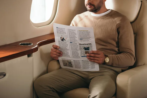 Vue recadrée d'un homme barbu tenant un journal en jet privé — Photo de stock